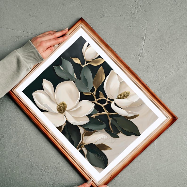 K&ouml;nnte beinhalten: Ein gerahmter Kunstdruck mit wei&szlig;en Magnolienbl&uuml;ten mit goldenen Akzenten und dunkelgr&uuml;nen Bl&auml;ttern. Das Kunstwerk ist vor einem dunklen Hintergrund in einem warm get&ouml;nten Holzrahmen gerahmt.