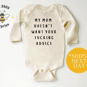 May include: Cream-colored baby bodysuit with long sleeves. The text "MY MOM DOESN'T WANT YOUR FUCKING ADVICE" is printed in black. A yellow circle with "SHIPS NEXT DAY" is on the right. A bee logo is on the left.