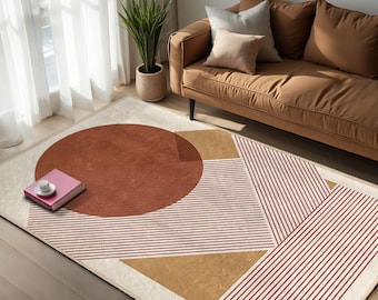 May include: A contemporary rug with a geometric pattern. It features a large rust-coloured circle, tan triangles, and red and white striped sections on a cream backdrop. A brown sofa with cushions and a potted plant are in the background.