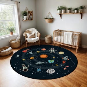 Pode incluir: Um tapete redondo preto e branco com tema espacial com um design de galáxia em espiral. O tapete apresenta planetas, estrelas, um foguete e um astronauta.