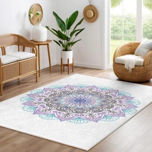 May include: A white area rug with a large purple and teal mandala design. The rug is in a living room setting with a wicker chair and a potted plant.