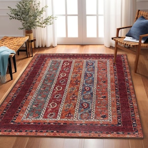 May include: A red, orange, blue, and white patterned rug with a traditional design. The rug has a dark red border with intricate details.