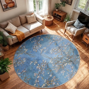 Puede incluir: Una alfombra redonda con fondo azul y diseño floral. La alfombra presenta un patrón de ramas florecientes con flores blancas y rosas. La alfombra está colocada sobre un suelo de madera en un salón.