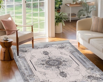 May include: A light grey and white area rug with a detailed floral pattern in black. The rug has a distressed look and a light blue border.