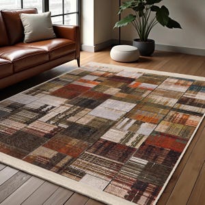May include: A multi-coloured area rug with a patchwork design featuring squares of various shades of brown, orange, red, and green. The rug has a white border.