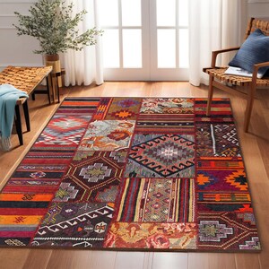 Puede incluir: Una alfombra de patchwork colorida con patrones geométricos en tonos rojos, naranjas, marrones y azules. La alfombra está hecha de tejido tejido y tiene un borde con flecos.
