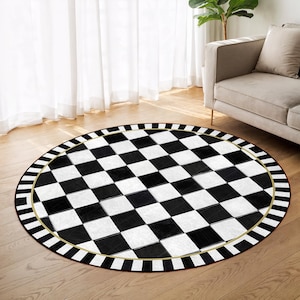 May include: A round rug with a black and white checkerboard pattern. The rug has a black and white striped border with a gold-colored inner ring. The rug is placed on a hardwood floor.