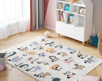 May include: A white play mat with a colorful alphabet design featuring animals and letters. The mat includes illustrations of a bear, elephant, fox, iguana, koala, narwhal, owl, penguin, rabbit, sheep, tiger, vulture, x-ray fish, zebra, and whale.