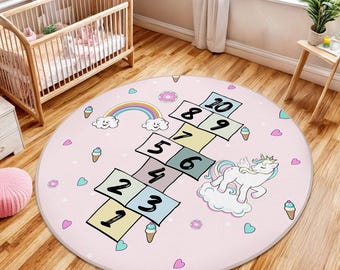 May include: A pink and white round play mat with a hopscotch game featuring numbers 1 through 10. The mat also has a unicorn, ice cream cones, rainbows, and hearts.