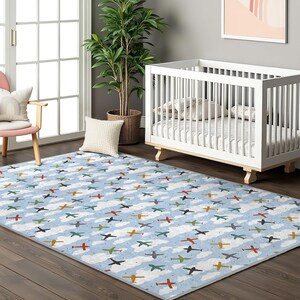 May include: A blue and white airplane patterned rug with clouds. The rug is in a nursery with a white crib and a white chair with a blue and white pillow.