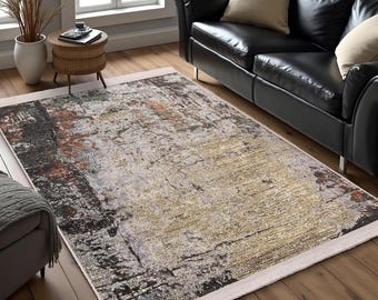 May include: Abstract area rug with a white border, featuring a distressed, textured design in shades of brown, beige, and gray. The rug is shown in a living room setting with a black leather sofa.