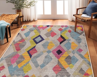 May include: A colorful geometric area rug with a white background and a pattern of pink, yellow, blue, and gray diamonds. The rug has a fringe border.