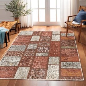 Puede incluir: Una alfombra de estilo patchwork con fondo crema y cuadrados de color marrón, beige y óxido con intrincados patrones.