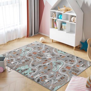 May include: A gray and white play mat with a road and city scene. The mat features a variety of colorful illustrations, including cars, houses, trees, and animals.