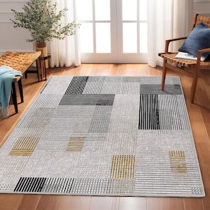 May include: A geometric patterned rug with black, white, and gold stripes. The rug has a modern design and is perfect for adding a touch of style to any room.