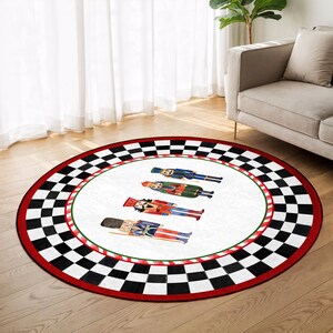 May include: A round area rug with a white center featuring four nutcracker illustrations. The rug has a red and green border, and a black and white checkered pattern around the edge. The rug is on a hardwood floor.