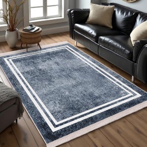 May include: A blue area rug with a white double border. The rug has a distressed, vintage look and is perfect for adding a touch of style to any room.