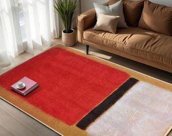 May include: Abstract art rug featuring a red, black and white design on a beige background. The rug is laid out on a wooden floor in front of a brown sofa.