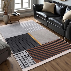 Peut inclure: Un tapis à motifs géométriques avec un schéma de couleurs blanc, gris, noir, marron et or. Le tapis a une bordure à franges et est fait d'un matériau doux et durable.