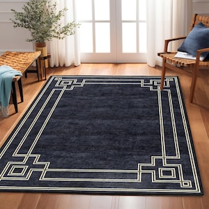May include: A dark blue rug with a white and gold geometric border. The rug has a subtle textured pattern and a modern design.