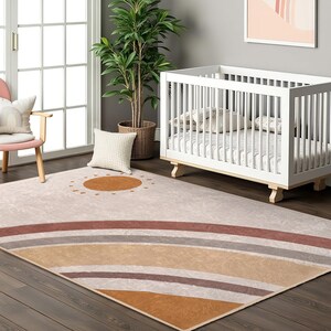 May include: A beige and brown area rug with a rainbow design and a sun in the centre. The rug is in a nursery with a white cot.