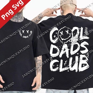 May include: Black t-shirt with white graphic text and design. The front of the shirt says "COOL DADS CLUB" in a circle. The back of the shirt has a melting smiley face and the words "COOL DADS CLUB".