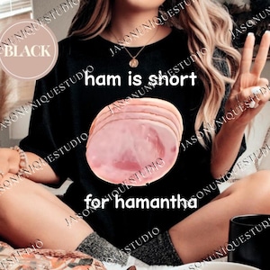 Puede incluir: Camiseta negra de cuello redondo con el texto "ham is short for hamantha" y un gráfico de jamón en rodajas. La palabra "BLACK" está en un círculo en la parte superior izquierda.