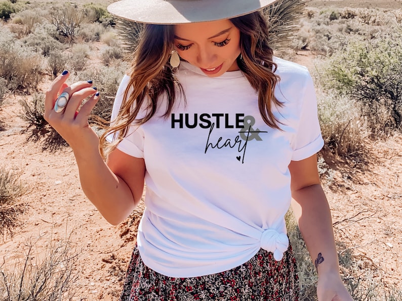 May include: White t-shirt with black text that reads "Hustle & heart" with a small heart symbol below the text.
