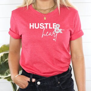 May include: A red t-shirt with the text "Hustle & heart" in white lettering. The text is in a modern, handwritten font.