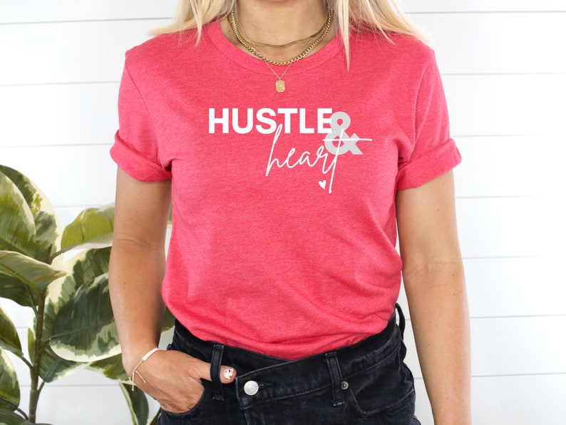 May include: A red t-shirt with the text "Hustle & heart" in white lettering. The text is in a modern, handwritten font.