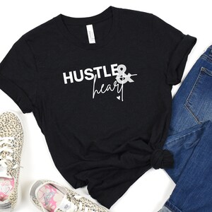 May include: Black t-shirt with white text that reads "Hustle & heart" with a small arrow and heart graphic.