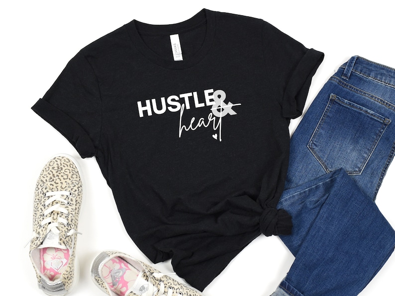 May include: Black t-shirt with white text that reads "Hustle & heart" with a small arrow and heart graphic.