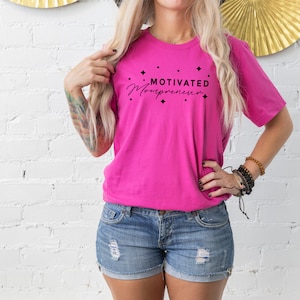 May include: A pink t-shirt with the text "Motivated Mompreneur" in black lettering with small stars around the text.