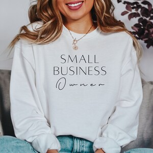 May include: White sweatshirt with the text "SMALL BUSINESS Owner" in black lettering.