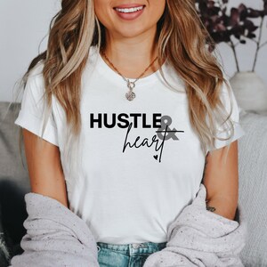 May include: White t-shirt with the text "Hustle & heart" in black lettering.