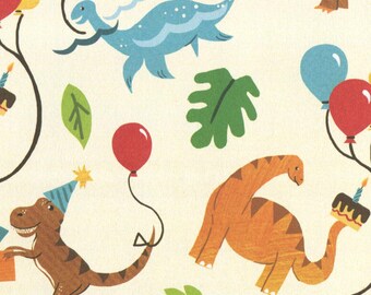 May include: Cream-coloured wrapping paper featuring a repeating pattern of dinosaurs, balloons, and birthday cakes. The dinosaurs are in shades of brown, blue, and orange, with green leaves. The paper includes text that says "100% Recycled Carbon Balanced Recyclable Vegan Inks Biodegradable Compostable".