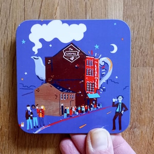 May include: A blue and red illustrated coaster featuring a building with the text "The Leadmill" and a line of people waiting outside. The building is shaped like a teapot with a cloud of steam above it. There is a crescent moon and stars in the sky.