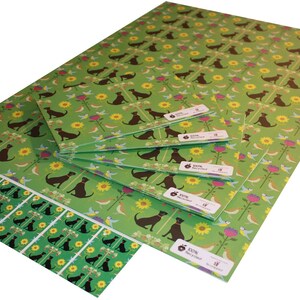 May include: Sheets of green wrapping paper with a repeating pattern of brown dogs, yellow sunflowers, pink flowers, and blue birds. The paper is labeled "100% Recycled".