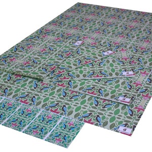 Puede incluir: Un conjunto de papel de regalo estampado en verde y azul con un dise&ntilde;o de p&aacute;jaros y flores. El papel est&aacute; doblado y apilado, con la hoja superior mostrando el dise&ntilde;o completo. El papel est&aacute; etiquetado con el nombre de la marca "Wrap It Up".