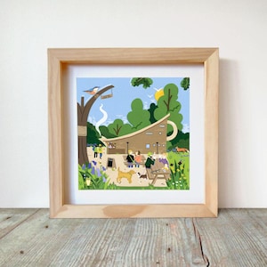 Puede incluir: Impresión artística enmarcada que representa una escena de café al aire libre. La ilustración presenta un edificio marrón con un techo en forma de taza, personas, perros y un pájaro en una rama de árbol. El cielo es azul con árboles verdes.