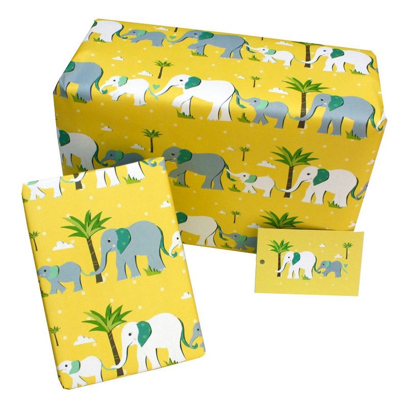 Pu&ograve; includere: Carta da regalo gialla con un motivo ripetuto di elefanti, palme e nuvole. Gli elefanti sono grigi e bianchi. Include un'etichetta regalo e una scatola avvolta.
