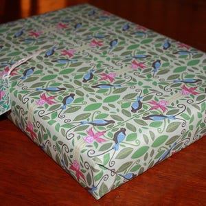 Puede incluir: Papel de regalo verde y blanco con un patr&oacute;n repetitivo de p&aacute;jaros azules y flores rosas.