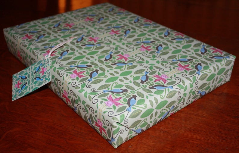 Puede incluir: Papel de regalo verde y blanco con un patr&oacute;n repetitivo de p&aacute;jaros azules y flores rosas.