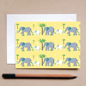 Pu&ograve; includere: Un biglietto di auguri con sfondo giallo con un motivo ripetuto di elefanti grigi, elefantini bianchi, palme e piccole nuvole bianche. Gli elefanti sono collegati da un disegno a forma di cuore. Sono visibili anche una busta e una matita.