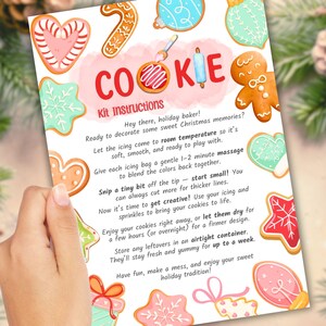 May include: A cookie decorating kit instruction sheet with colorful, decorated cookies. The sheet includes instructions for decorating cookies, with text that reads "COOKIE Kit Instructions". The cookies are in the shape of hearts, stars, and gingerbread people.