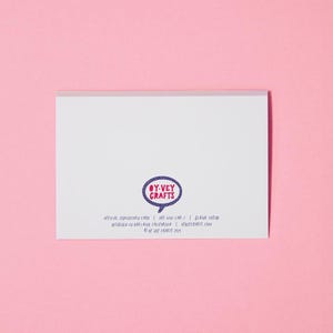 以下が含まれることがあります： ピンクの文字で「OY-VEY CRAFTS」と書かれた紫色の吹き出しが描かれた白いカード。カードには、「OFFICIAL JEWNICORN CARD | OFF-UNI-CAR- | BLANK INTIDE | DESIGNED IN GARLAND CALIFORNIA | OYVETCRAFTS.COM | &copy; OY-VEY CRAFTS 2015」というテキストも含まれています。