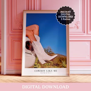 May include: A framed art print featuring a photograph of white cowboy boots and legs against a blue sky and desert landscape. The print includes the text "COWBOY LIKE ME" and "VOLUME 09 NO 11". A digital download badge is in the upper right corner.