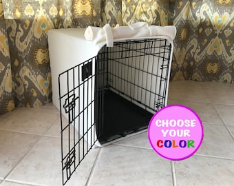 May include: A black wire pet crate featuring a white fabric cover draped over the top and sides. The crate has an open front door and a black plastic floor tray. A circular pink graphic overlay in the bottom right corner displays the text CHOOSE YOUR COLOR.