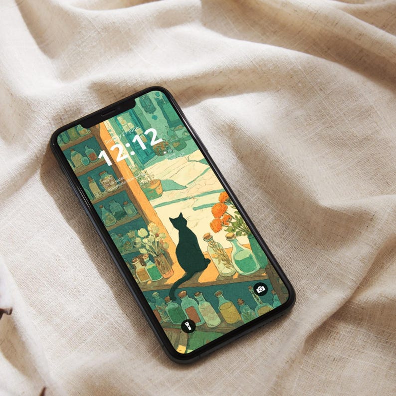 May include: A black smartphone displays a whimsical illustration of a black cat perched on a shelf, overlooking a scene with bottles and flowers. The time 12:12 is visible on the screen. The phone rests on a beige, textured surface.