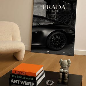 Old money fashion style black-and-white Porsche artwork with Prada-inspired text, creating a moody luxury aesthetic. This elegant print is ideal for old money prints, old money aesthetic décor, and upscale fashion poster displays. Perfect for lovers of luxury prints, luxury car poster décor, and designer interiors seeking prada fashion inspired poster styling and dark elegance minimalist fashion home decor accents.